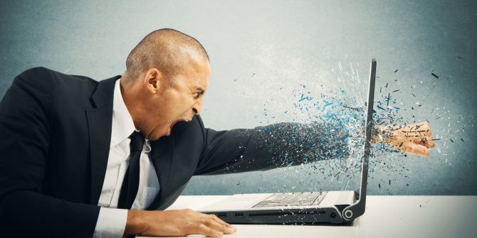 Hombre rompe pantalla de ordenador portátil con el puño Hombre rompe pantalla de ordenador portátil con el puño