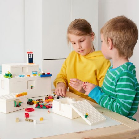 Piezas LEGO en caja IKEA, niños jugando