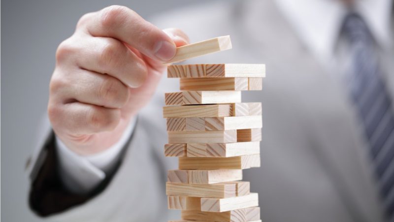 directivo colocando bloques de madera en una torre simbolo de planificacion y gestion de riesgos Merca2.es