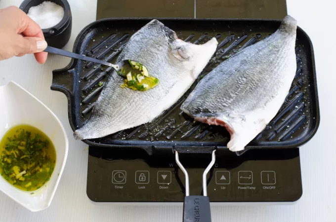 dorada al ajillo cocinandose en la plancha Merca2.es