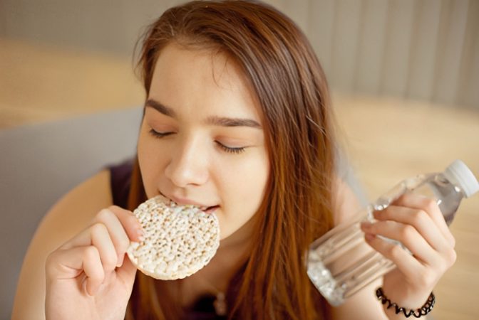 Chica comiendo galleta de arroz