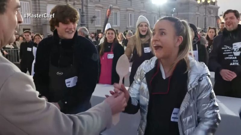 Cris Ortiz al fondo con gorro observa a una ganadora de la cuchara en MasterChef Merca2.es