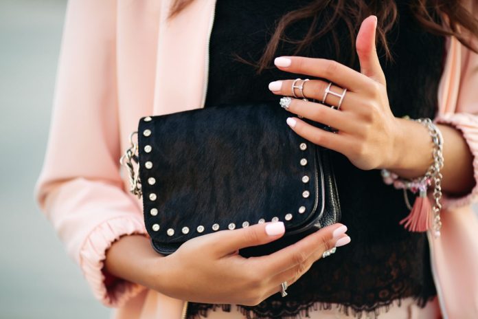 female-hands-with-beautiful-nail-polish-rings-holding-small-black-bag Parfois tiene el bolso clutch perfecto para ceremonias a un precio con el que no pueden competir ni Bimba y Lola ni Tous
