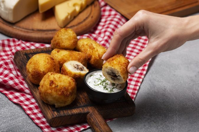 close up hand holding food croquette Merca2