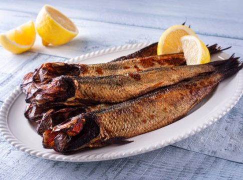 A plate of delicious smoked herring kippers with lemon on a wood table top. Mucho Omega 3, casi nada de mercurio: el pescado poco conocido en España que es el más nutritivo