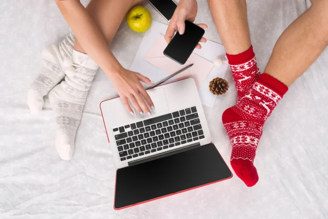 caucasian couple home using internet technology laptop phone people sitting floor coloured socks christmas love lifestyle concept Merca2.es
