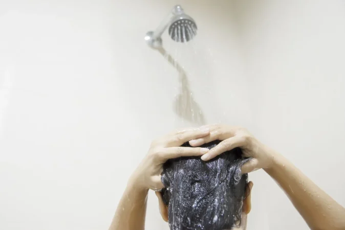 ¿Por qué no es recomendable ducharse con agua muy caliente? 20 Merca2.es lady using shampoo wash clean her hair bathroom with splash shower spray water Merca2.es