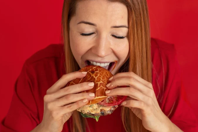 high angle young woman eating burger Merca2.es