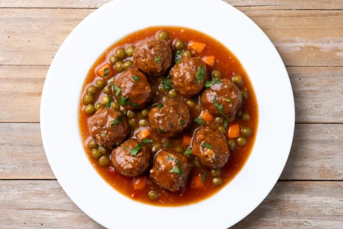 meatballs green peas carrot with tomato sauce wooden table 1 Merca2.es