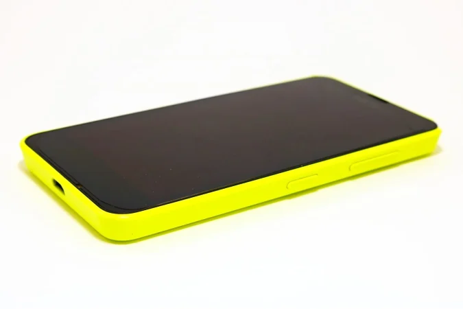 yellow mobile phone with black touch screen placed white background Merca2.es