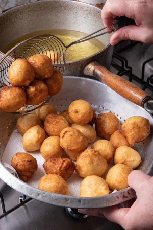 brazilian sweet called bolinho de chuva being taken from frying pan with oil selective focus Merca2.es