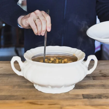 Potaje de vigilia: El clásico de la Semana Santa española 63 Merca2.es elderly hands putting tasty soup plate kitchen 1 Merca2.es