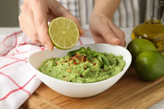 female hands hold lime bowl with guacamole Merca2.es