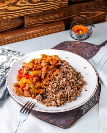front view fried meat slices along with buckwheat inside white plate brown wooden desk surface Merca2.es