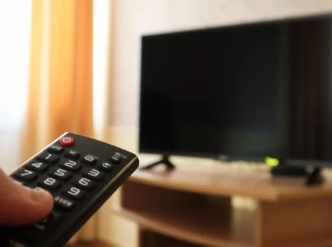 hand-holding-television-remote-control-surfing-programs-television-watch-turn-off-tv-living-room-bedroom-black-screen-nightstand-copy-space Te sube la factura sin usar nada: estos tres electrodomésticos tienen la culpa