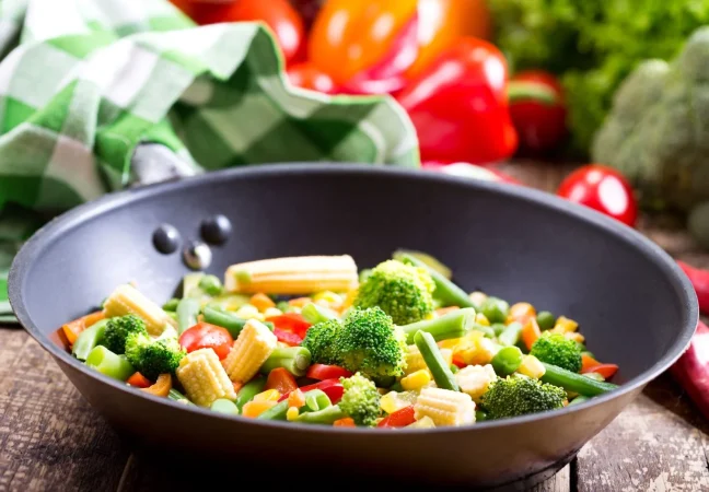 Salteado de verduras: Un acompañamiento saludable y delicioso 53 Merca2.es stir fried vegetables pan wooden table Merca2.es