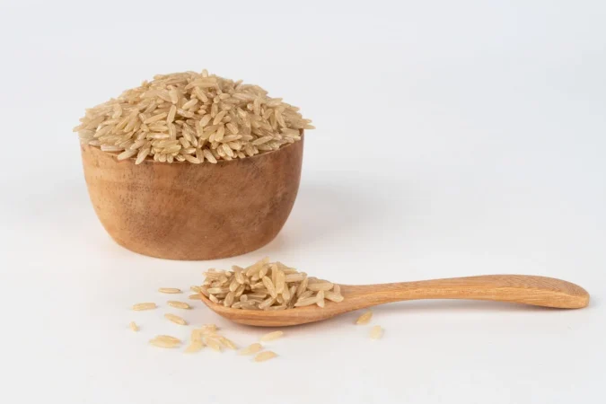 Arroz integral perfecto: El truco para que nadie note la diferencia (o casi) 84 Merca2.es arroz integral en un cuenco de madera y cuchara desbordando y esparcido por el suelo Merca2.es