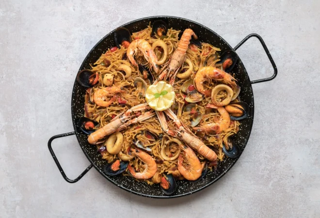tiro de vista superior de deliciosa paella con mariscos y aros de cebolla Merca2.es