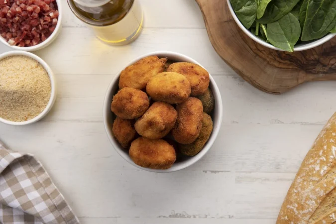 comida que contiene croquetas con tocino y un vaso de cerveza Merca2.es