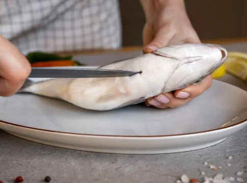 vista-frontal-cocinero-limpiando-pescado-en-la-cocina