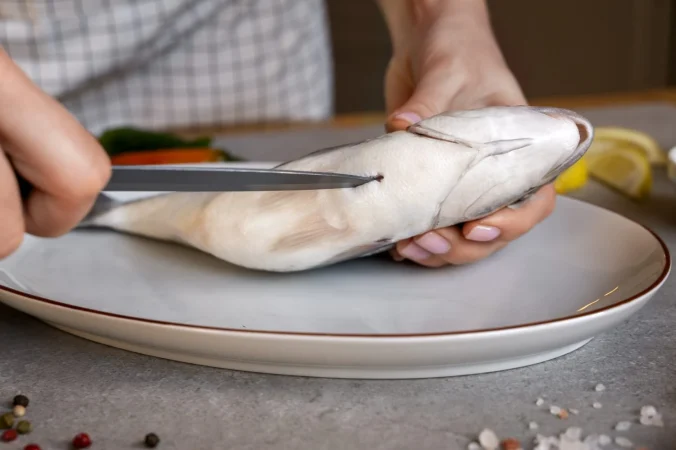 vista frontal cocinero limpiando pescado en la cocina Merca2.es