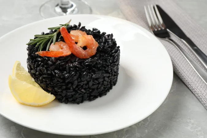 delicioso risotto negro con camarones y limon en un primer plano de mesa de marmol Merca2.es