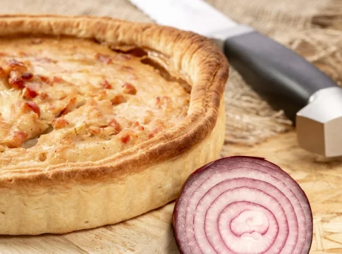 pastel-de-cebolla-francesa-con-tocino-en-la-tabla-de-la-cocina-cebolla-cortada-y-cuchillo-en-la-mesa-de-la-cocina-de-cerca quiche Lorraine