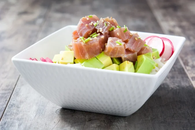 poke bowl de atun hawaiano con aguacate rabanos y semillas de sesamo en mesa de madera Merca2.es
