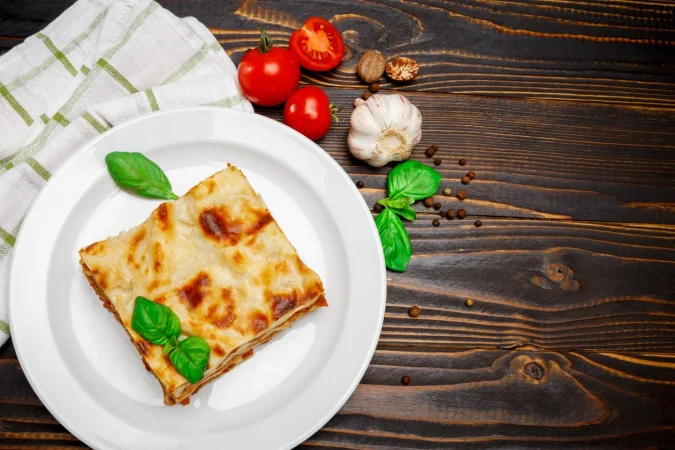 Lasaña de verduras: un clásico italiano con alma vegetal 48 Merca2.es porcion de sabrosa lasana sobre fondo de madera Merca2.es