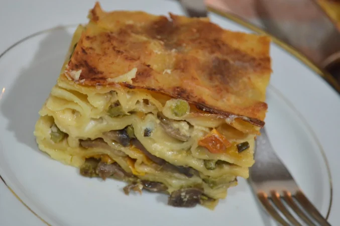 Lasaña de verduras: un clásico italiano con alma vegetal 53 Merca2.es primer plano de carne con salsa en el plato Merca2.es