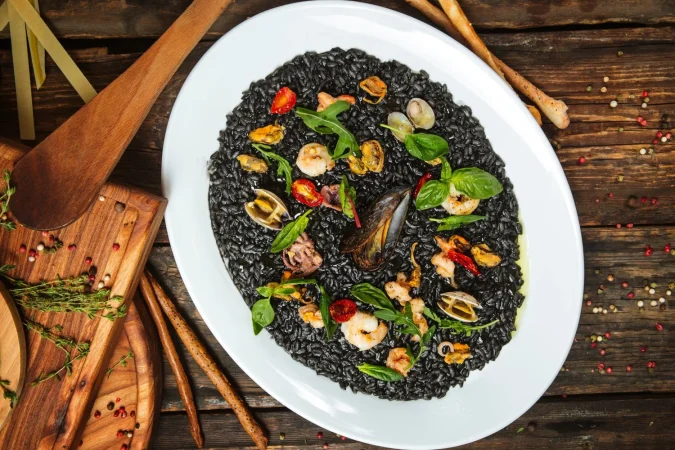 vista superior de risotto negro con mejillones en el plato blanco Merca2.es