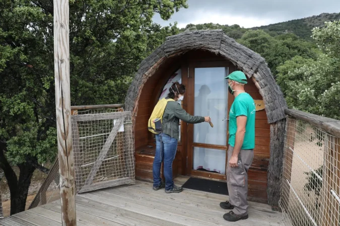 Un trabajador del camping le enseña a una clienta una Cabaña en el árbol del Camping Monte Holiday en Gargantilla del Lozoya. Agencias