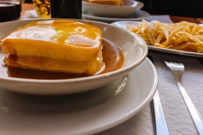 sandwich tradicional portugues francesinha con copa de vino y patata frita cocina portuguesa Merca2.es