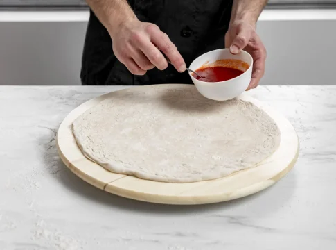 hombre-de-alto-angulo-esparcir-salsa-de-tomate-sobre-masa-de-pizza