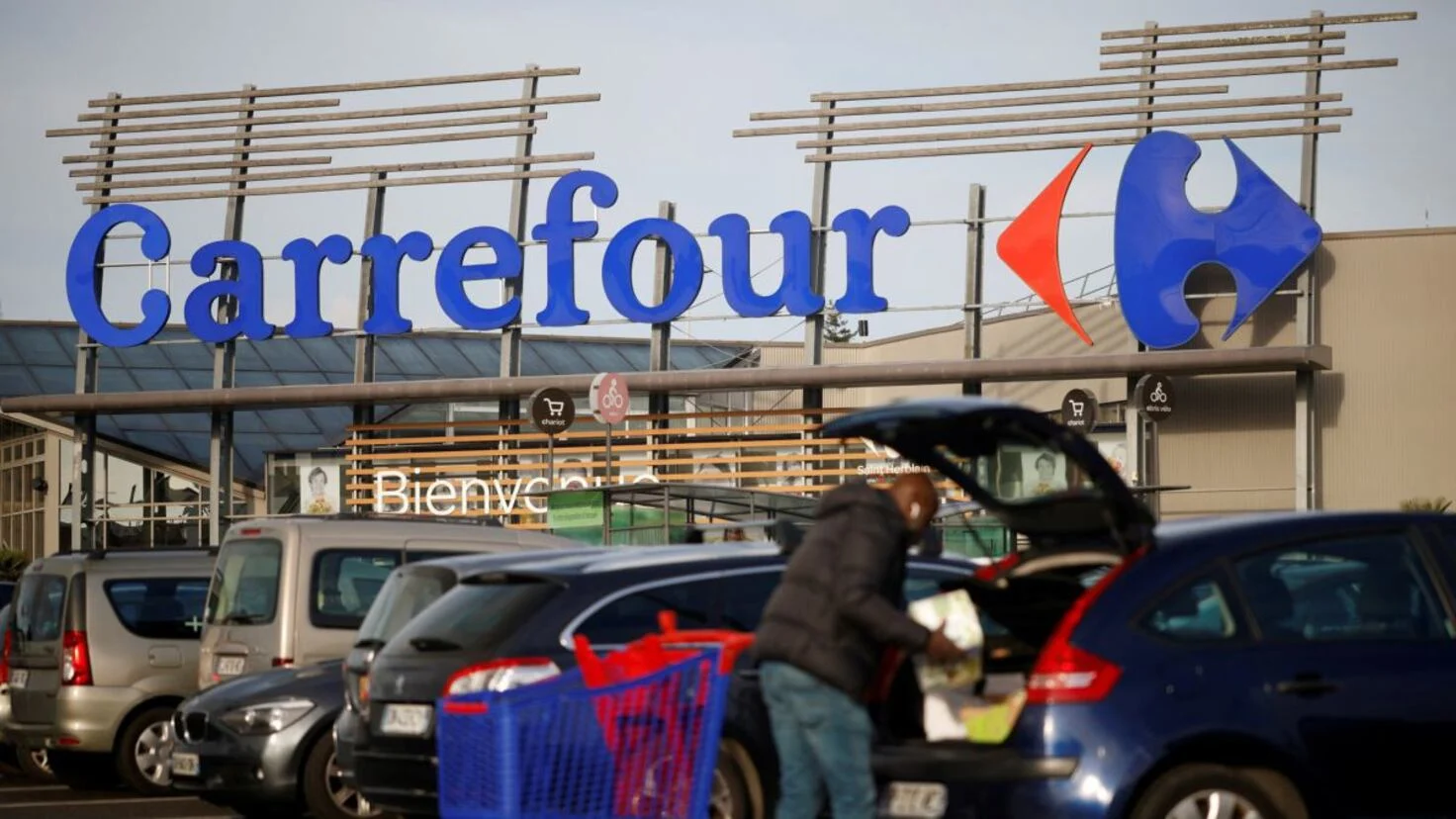 Un local de Carrefour con un cliente cargando la compra en el coche