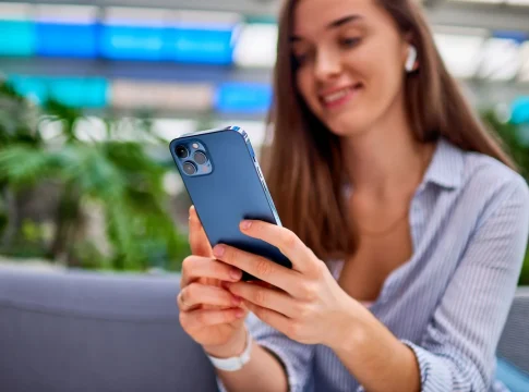 moderno-atractivo-casual-sonriente-elegante-milenario-mujer-llevando-auriculares-inalambricos-utilizar-telefono-para-en-linea-navegacion-y-charlar