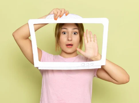 una-vista-frontal-joven-hermosa-en-camiseta-rosa-posando-con-papel-en-forma-de-tv-blanca-en-verde
