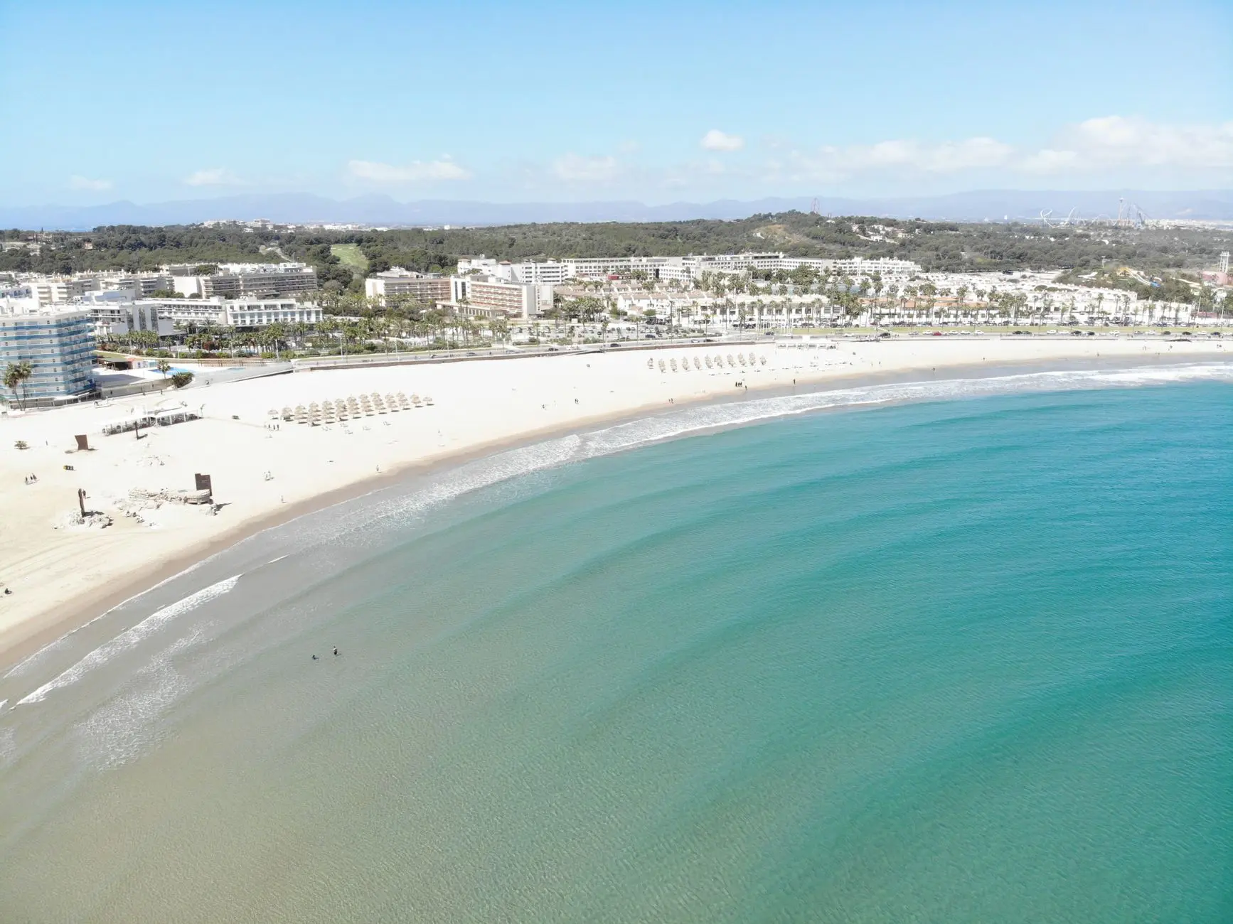 Impresionante vista aérea de un resort en la playa en Cataluña, que muestra aguas cristalinas y playas de arena.