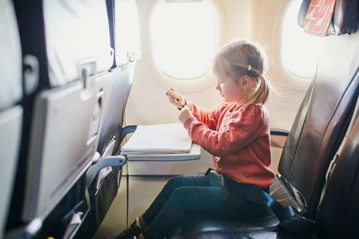 viaje en avión Una niña se entretiene dibujando en un avión