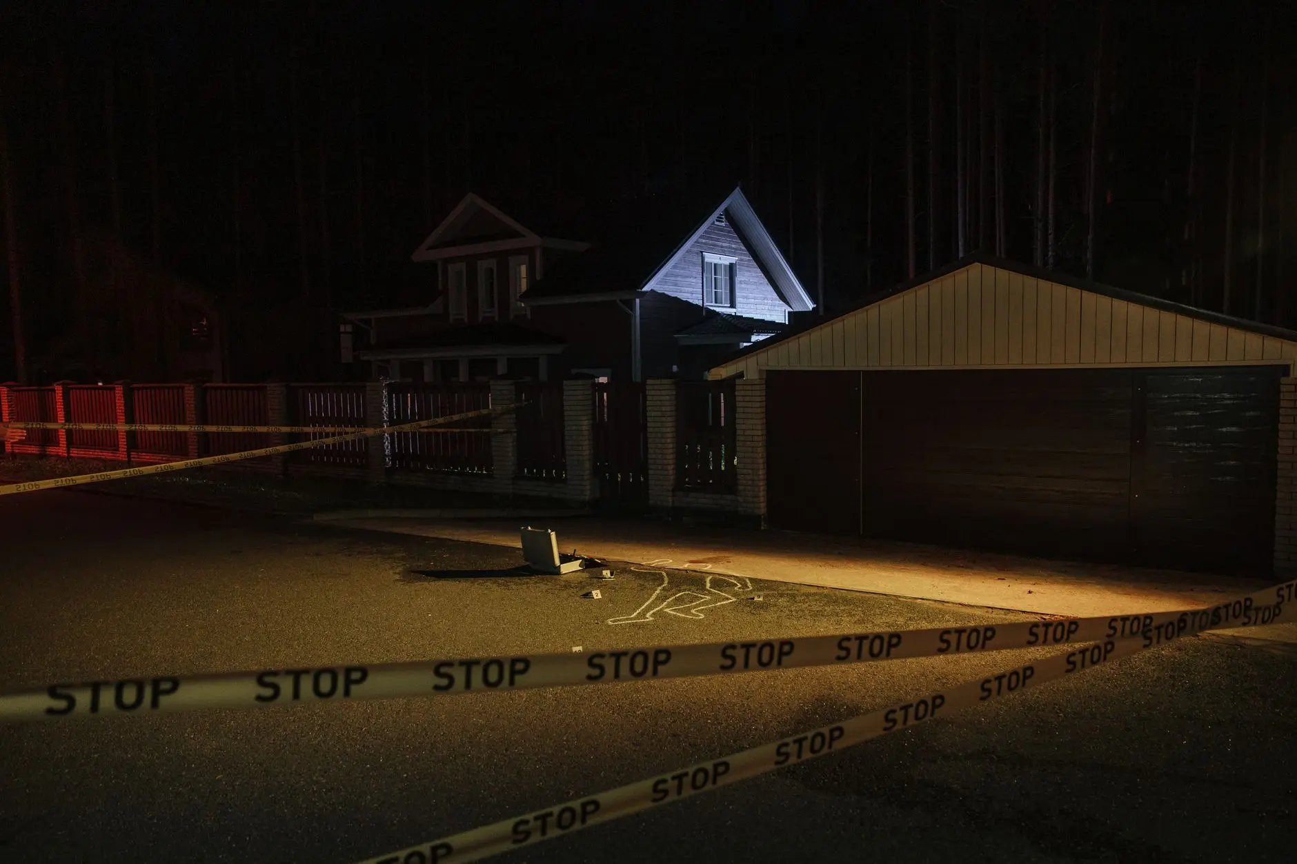 Escena del crimen suburbano nocturno con evidencia forense marcada en la acera.