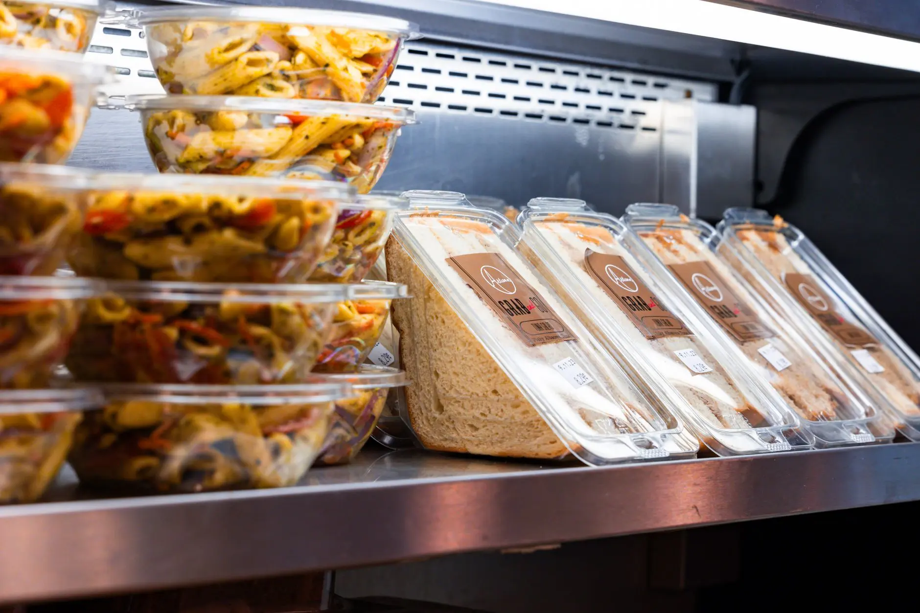 Consumo cambia las etiquetas de los supermercados: 5 productos que perderán la calificación de "saludables" en octubre 10 Merca2 Deliciosas ensaladas de pasta listas para comer y sándwiches expuestos en una nevera de tienda.