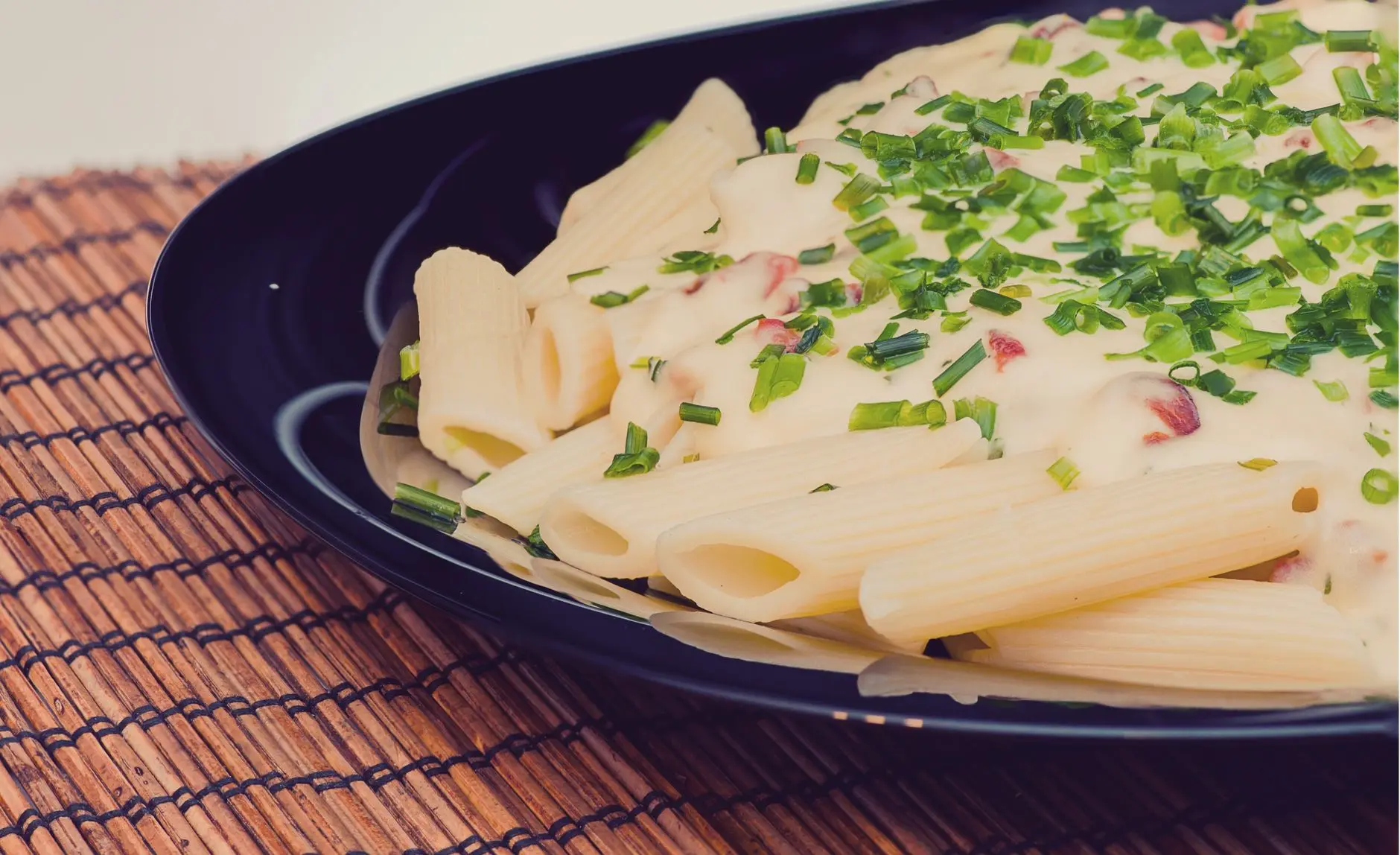 Deliciosa pasta penne con salsa de queso cremoso, decorada con hierbas frescas.