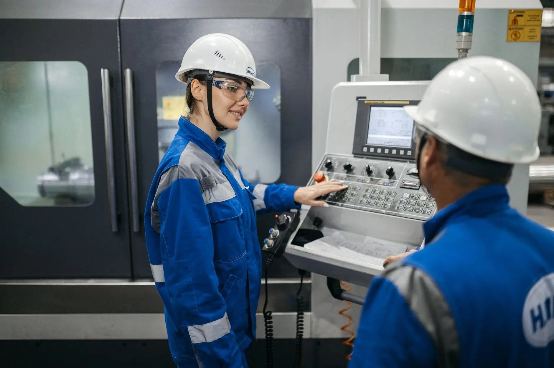 Dos trabajadores industriales con equipo de protección operan una máquina en una fábrica rusa.