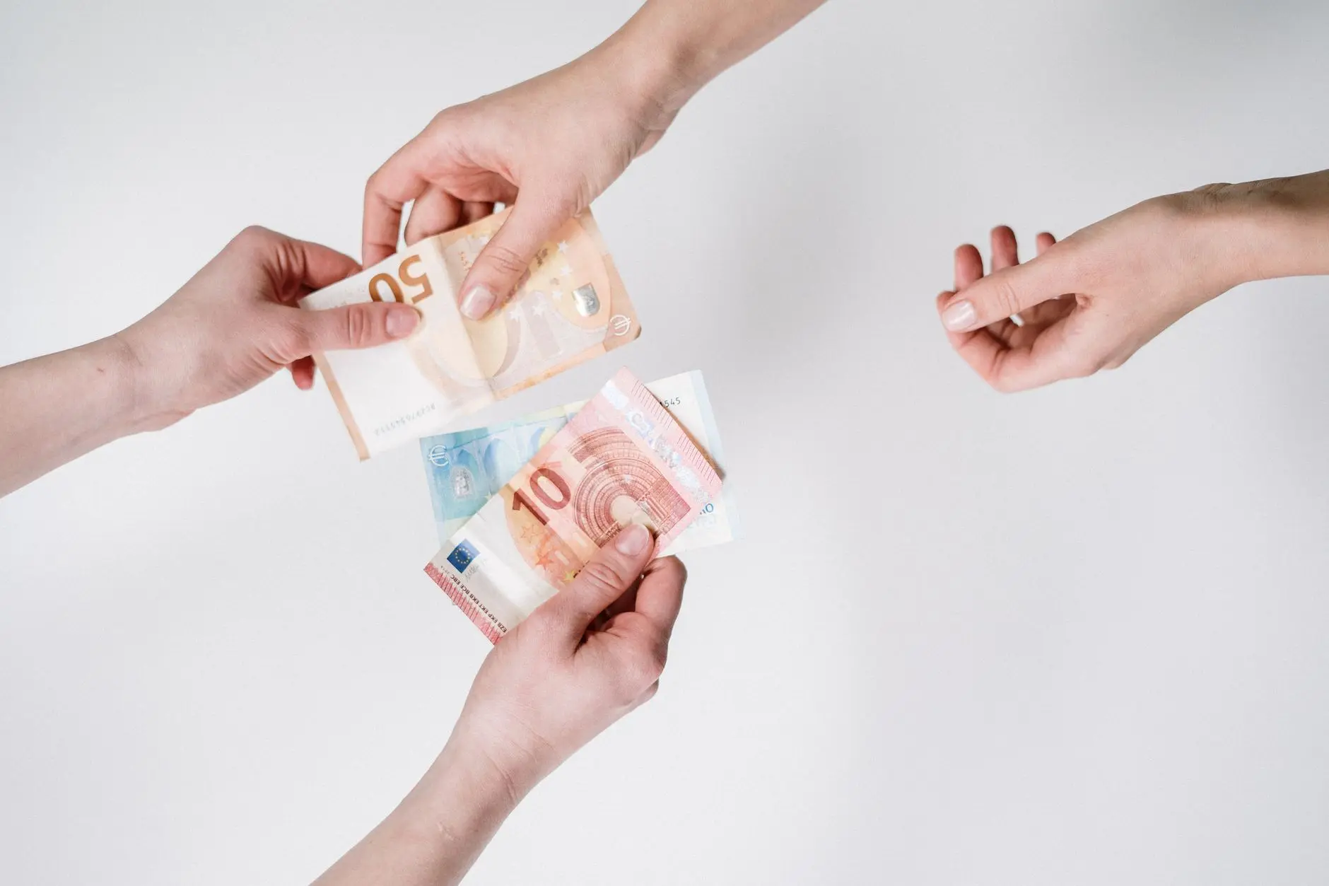Primer plano de manos intercambiando billetes de euro, simbolizando comercio de divisas y transacciones financieras.