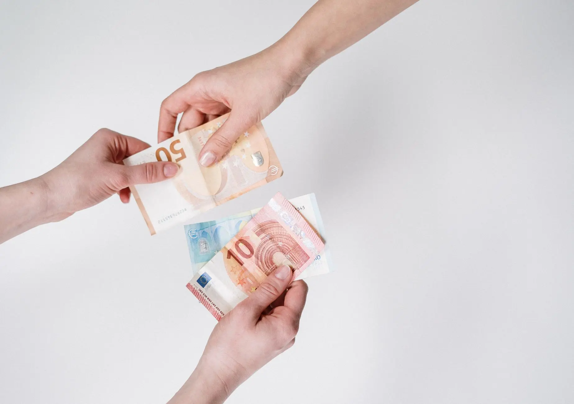 Close-up de manos intercambiando billetes de euro, simbolizando finanzas y transacción.