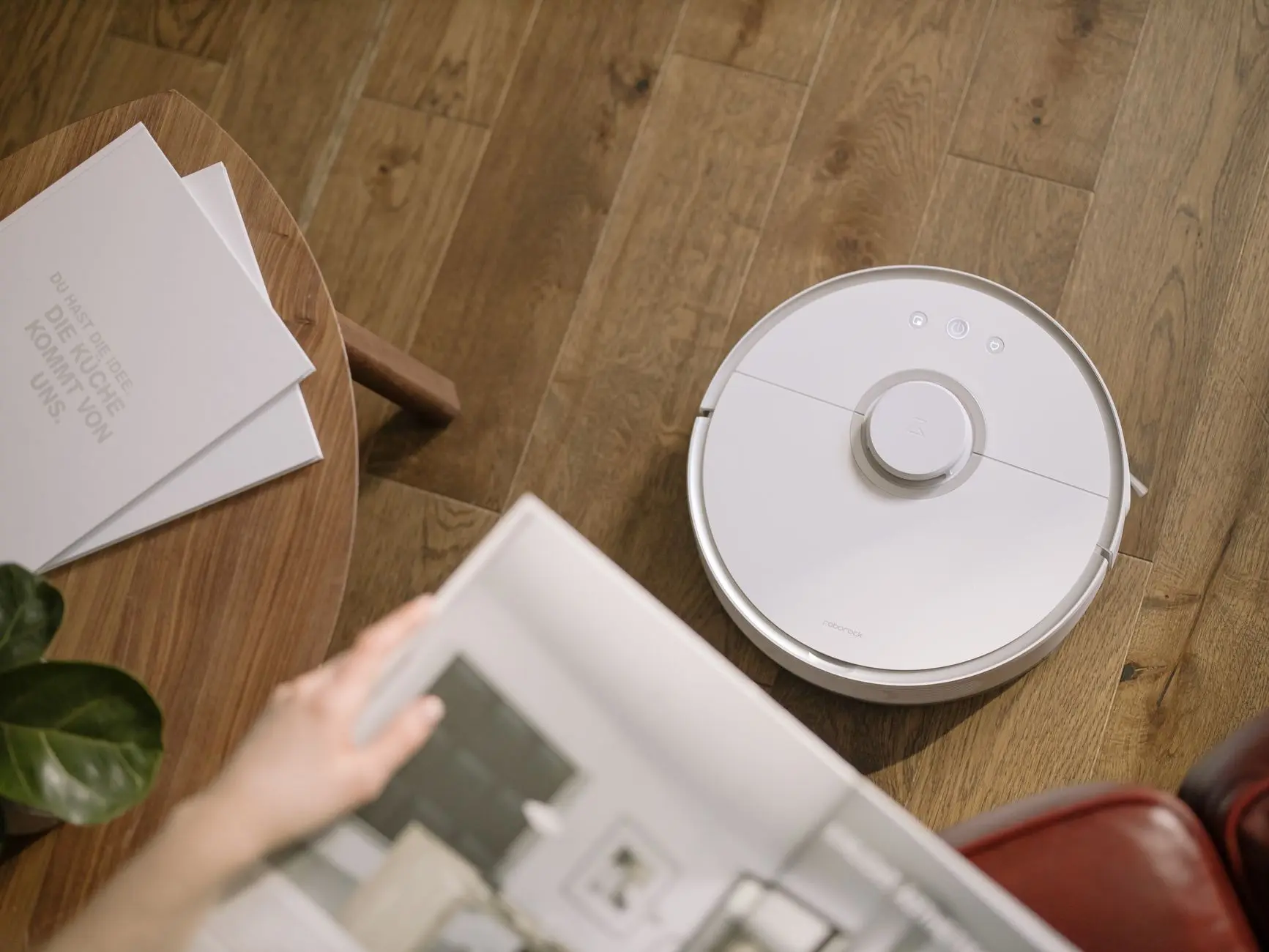 Una elegante aspiradora robótica que opera sobre un suelo de madera, simbolizando la tecnología moderna del hogar.