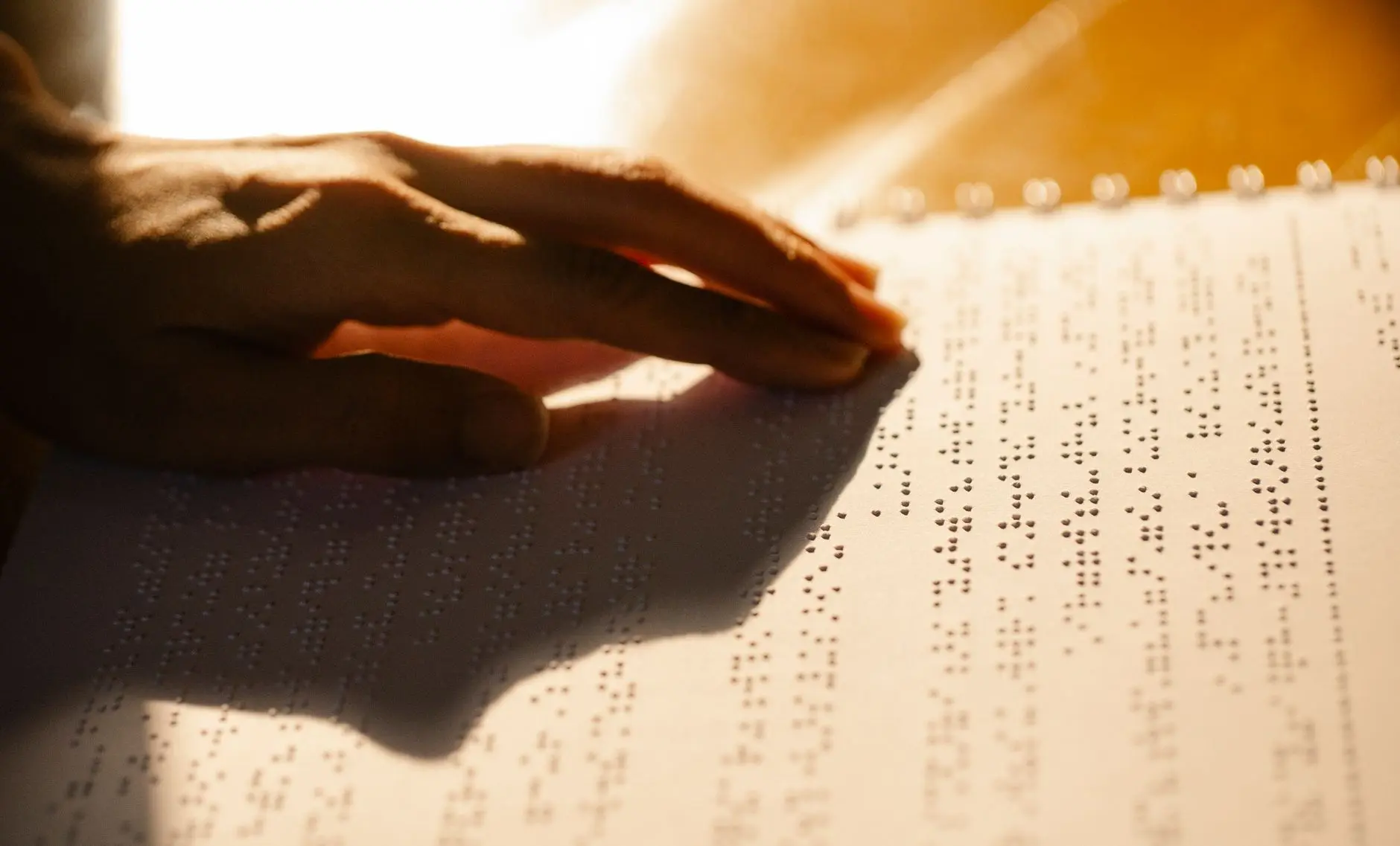 Una toma en primer plano de una mano leyendo un libro en braille, simbolizando la alfabetización táctil para personas con discapacidad visual.