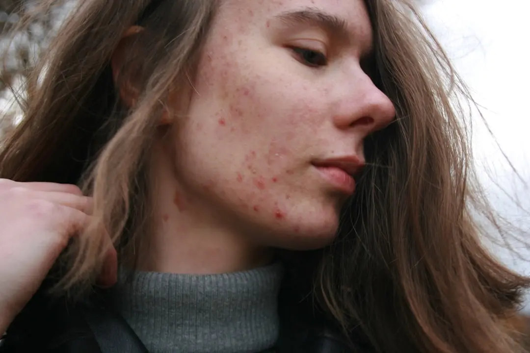 A woman with long brown hair wearing a grey turtleneck sweater
