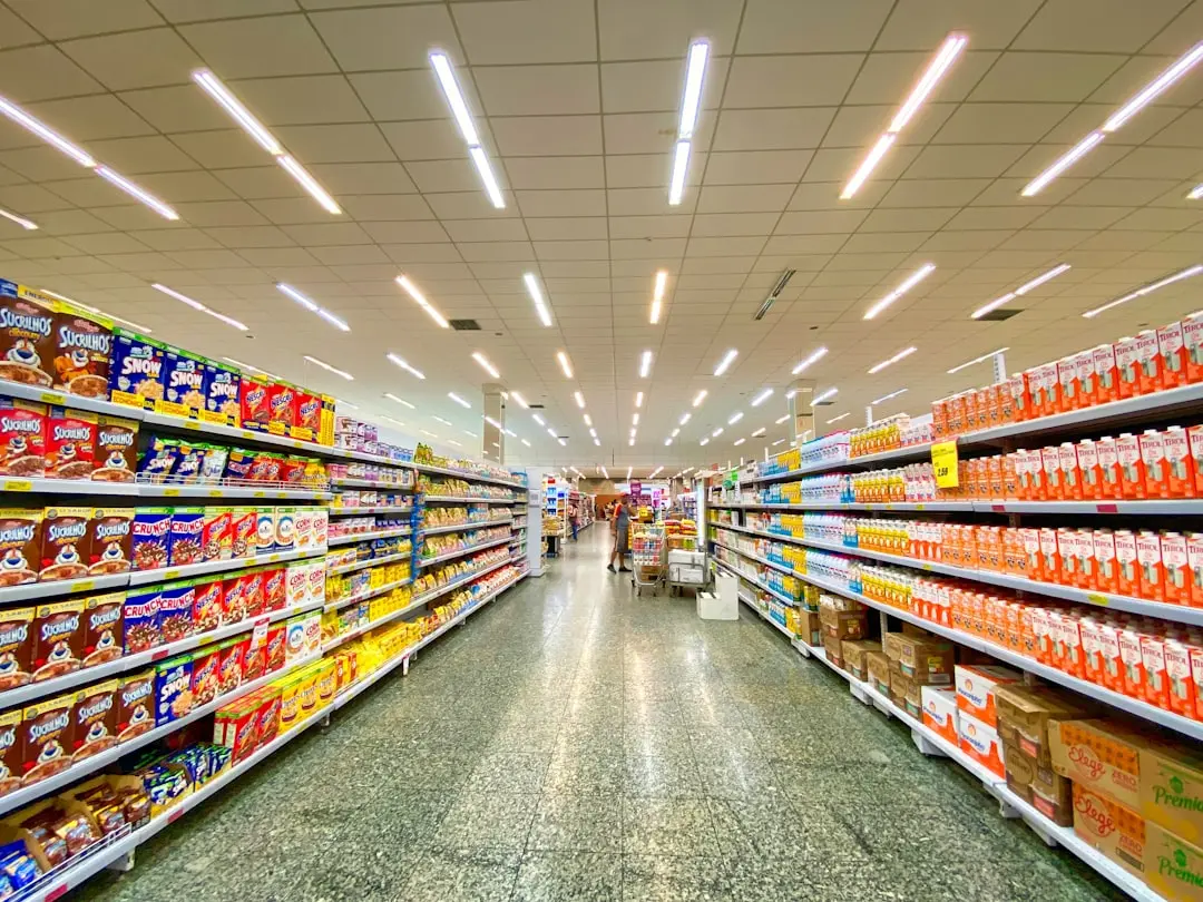 A grocery store aisle with shelves stocked with cereal boxes and milk cartons