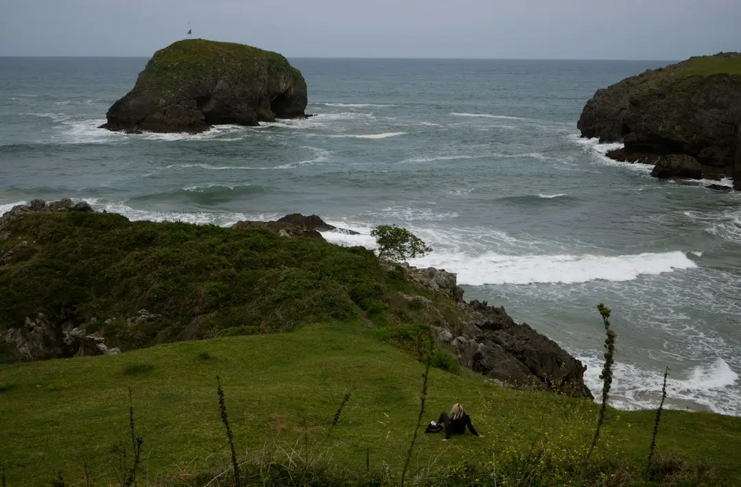 Green coastal cliffs overlook ocean waves and rocky islands